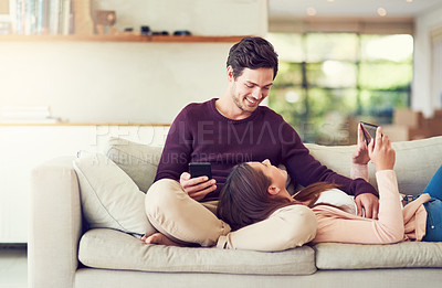 Buy stock photo Tablet, cellphone and couple relaxing on sofa for entertainment together in living room at home. Happy, love and people online networking on a phone and digital technology in lounge at apartment.