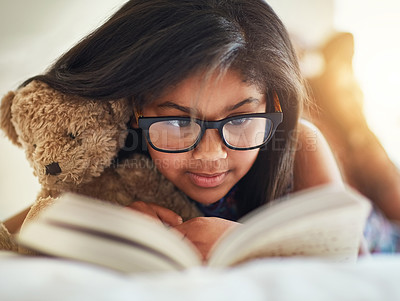 Buy stock photo Shot of a cute little girl reading a book in her bedroom