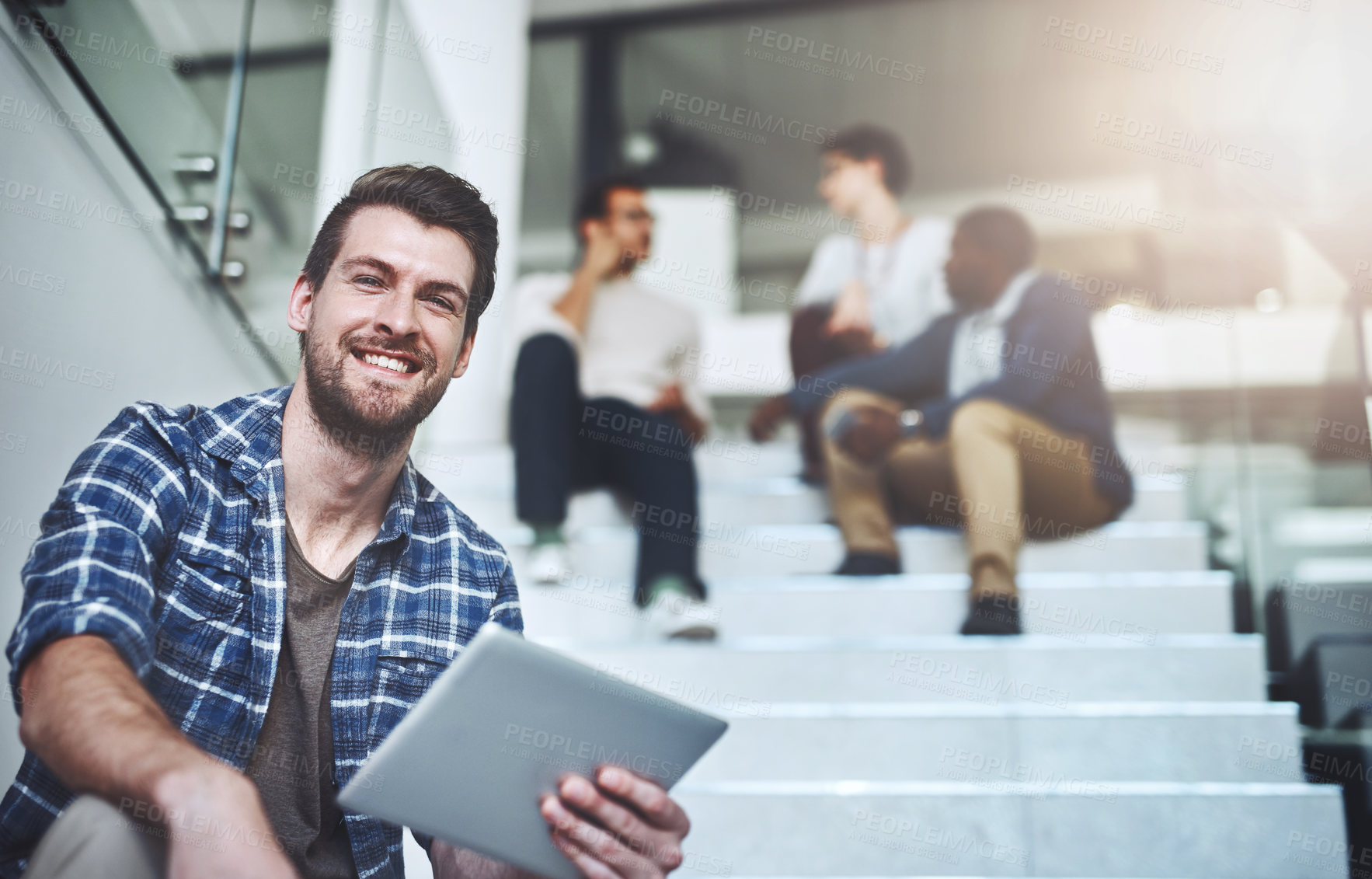 Buy stock photo Portrait of a young designer using a digital tablet with his colleagues in the background