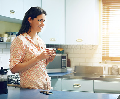 Buy stock photo Shot of an attractive young woman having a cup of coffee at home
