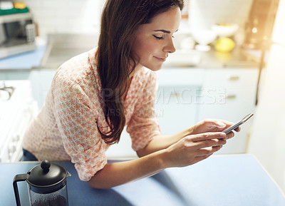 Buy stock photo Shot of an attractive young woman using a mobile phone at home