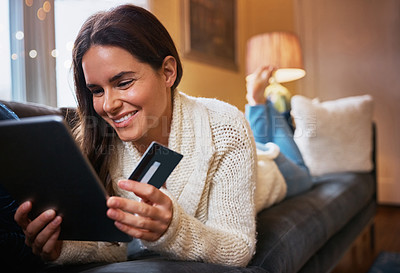 Buy stock photo Shot of an attractive young woman using a digital tablet and credit card on the sofa at home