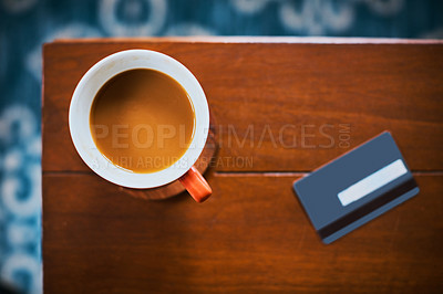 Buy stock photo High angle shot of a cup of coffee and credit card on a table