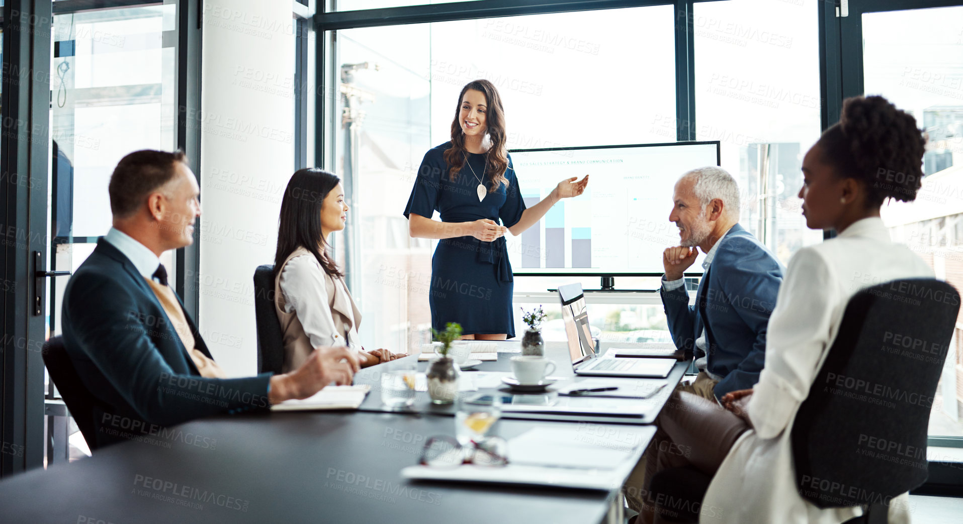 Buy stock photo Business woman speaker in an investment meeting with financial data on a boardroom screen. International executive team listening to a presentation. Finance worker talking at a partnership proposal