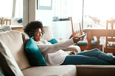 Buy stock photo Black woman, watching tv and relax on couch with remote, home and happiness for me time, comedy or show. African girl, television and happy for movie, video or search on living room sofa in apartment