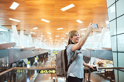 Buy stock photo Cropped shot of an attractive young woman taking selfies while standing in an airport