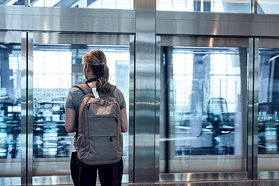 Buy stock photo Rearview shot of an unrecognizable young woman standing in an airport