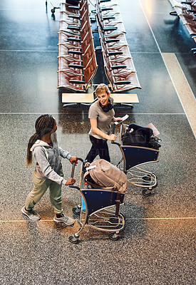 Buy stock photo High angle shot of two attractive young women walking through an airport