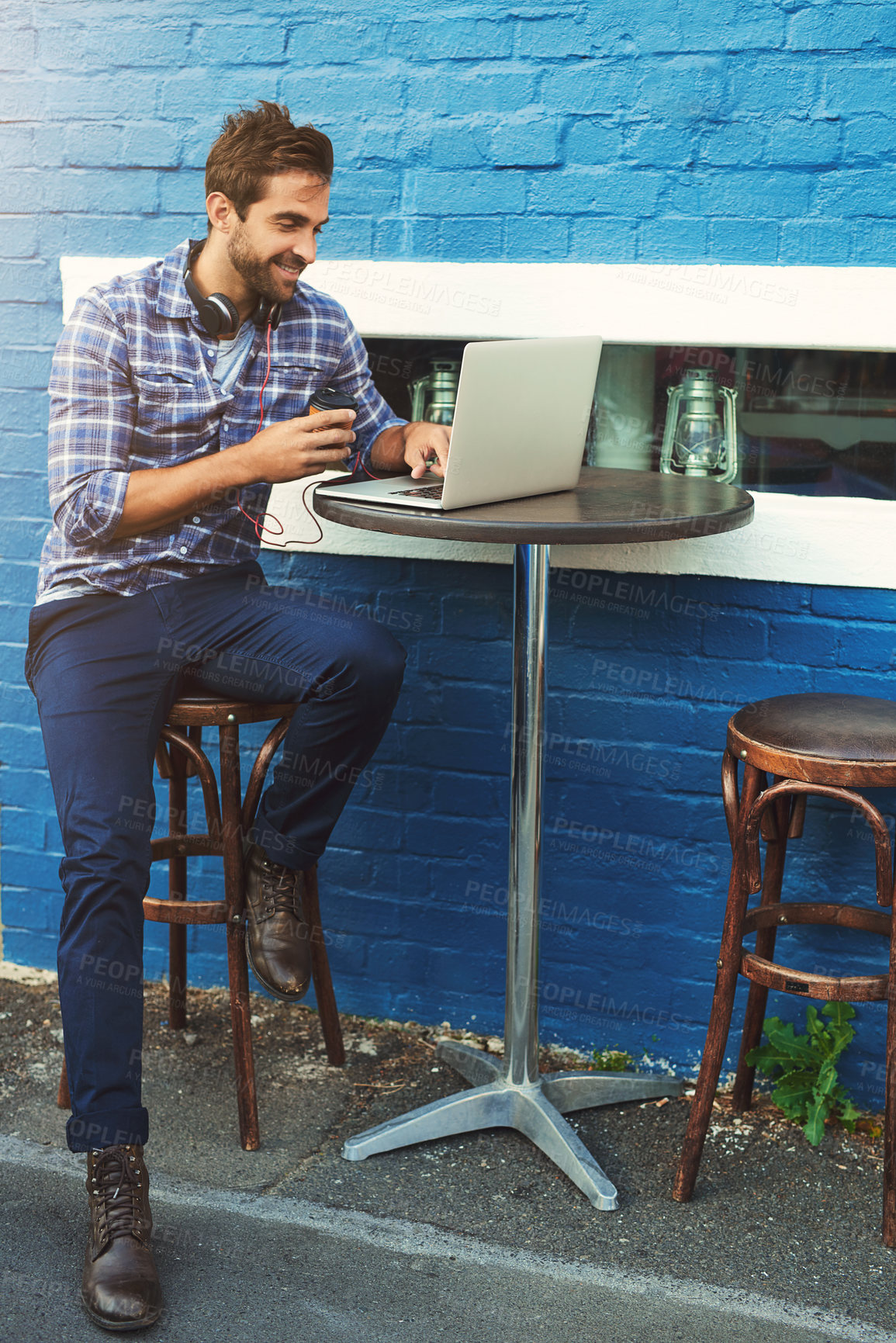 Buy stock photo Man, laptop at coffee shop in city as freelancer or content creator on travel blog, research or influencer. Male person,  smile and street cafe in Italy for writing article, brick wall or remote work
