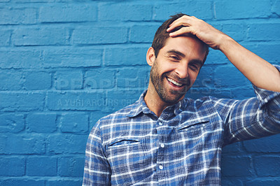 Buy stock photo Cropped shot of a handsome young man posing against a blue wall