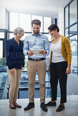 Buy stock photo Shot of a group of creatives working together on a digital tablet in an office