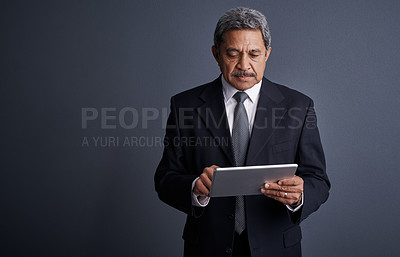 Buy stock photo Studio shot of a mature businessman using his digital tablet