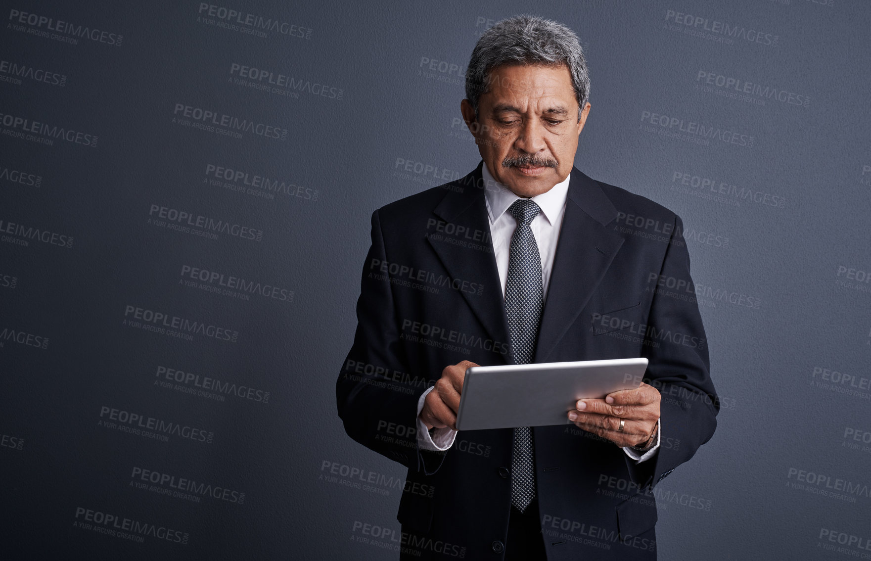 Buy stock photo Studio shot of a mature businessman using his digital tablet