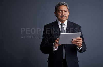 Buy stock photo Studio shot of a mature businessman using his digital tablet