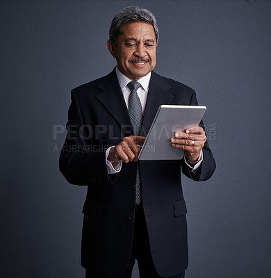 Buy stock photo Studio shot of a mature businessman using his digital tablet