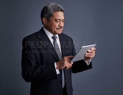 Buy stock photo Studio shot of a mature businessman using his digital tablet