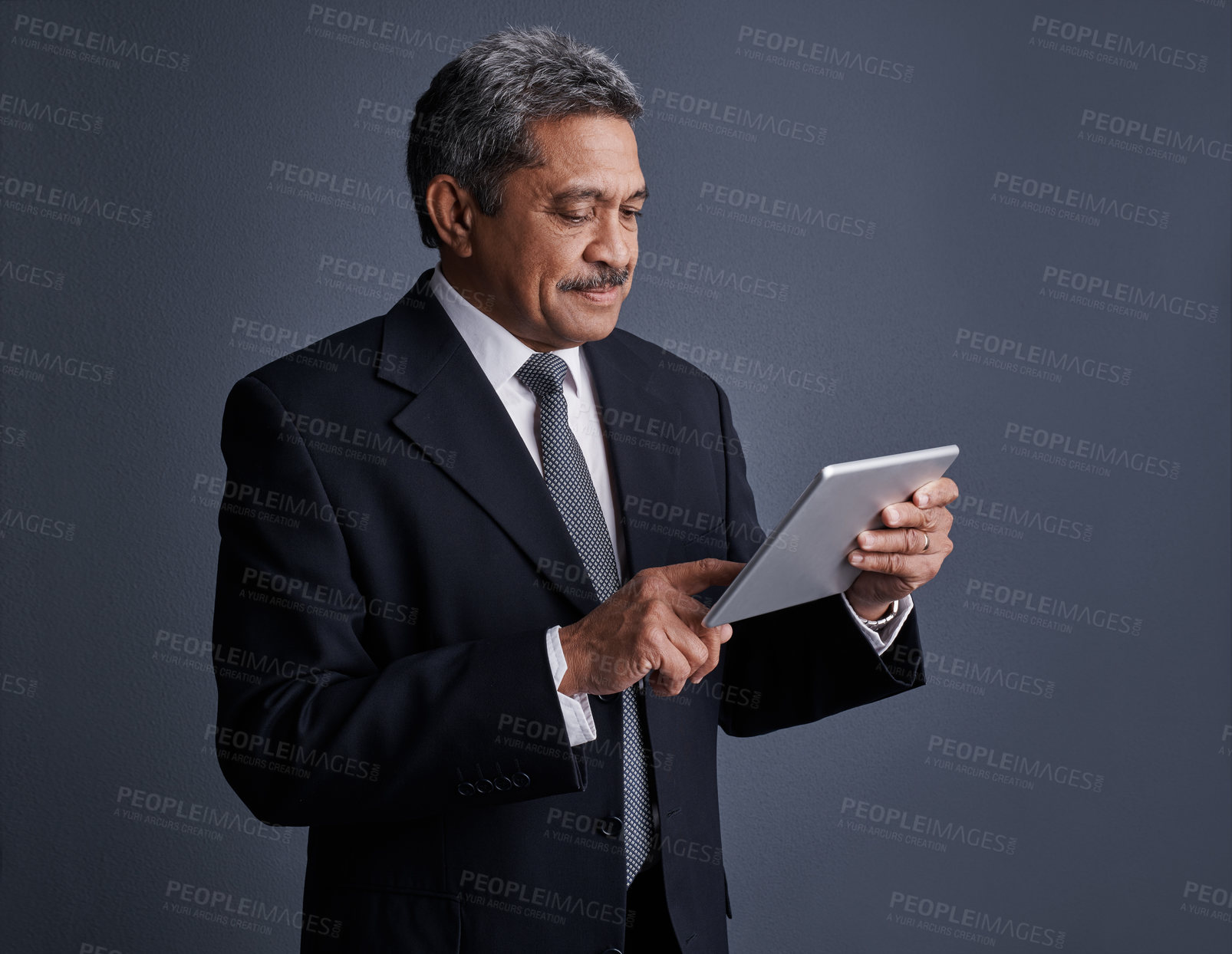 Buy stock photo Studio shot of a mature businessman using his digital tablet