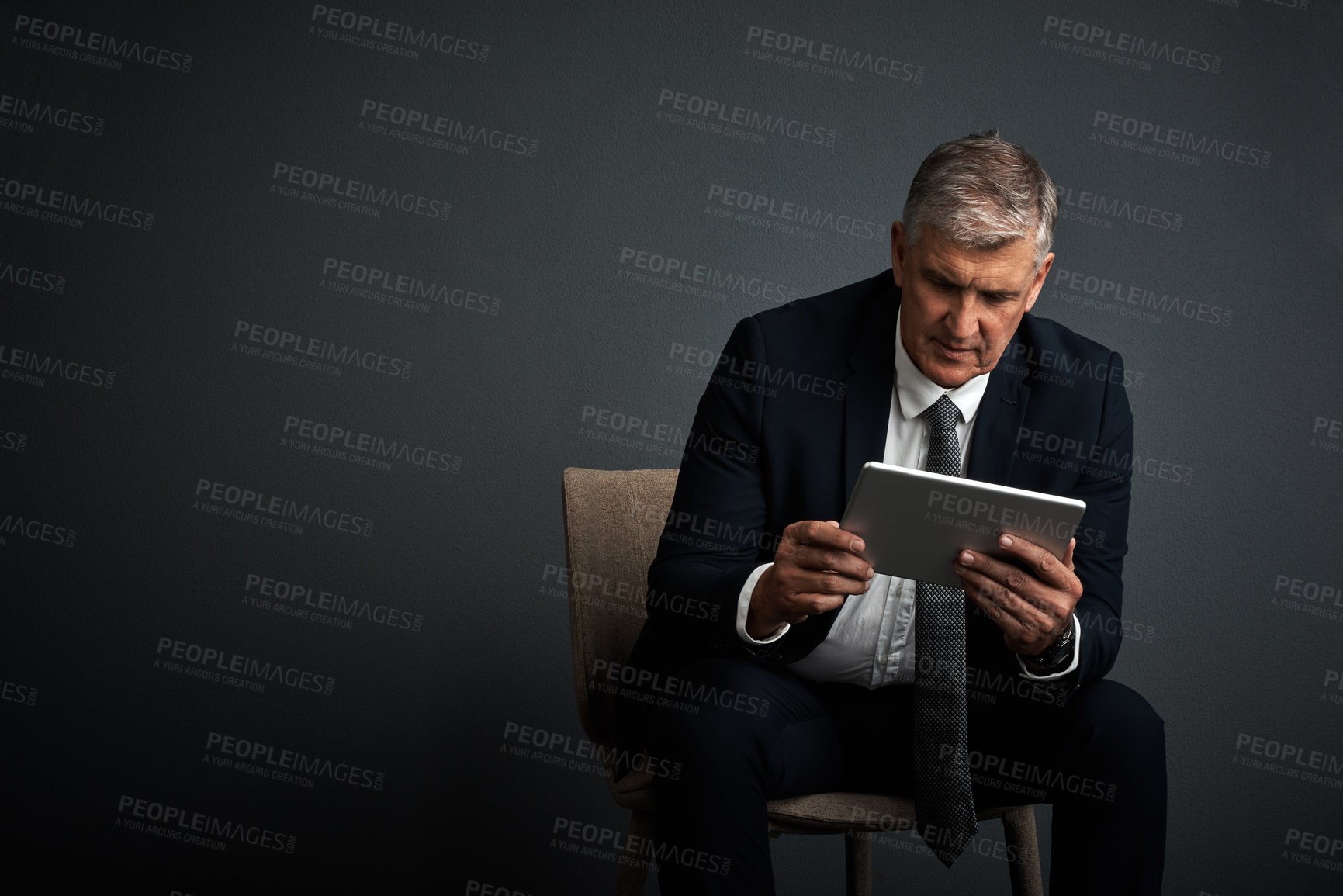 Buy stock photo Studio shot of a mature businessman using his digital tablet