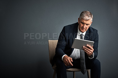 Buy stock photo Studio shot of a mature businessman using his digital tablet