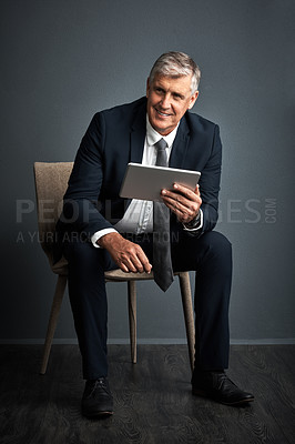 Buy stock photo Studio shot of a mature businessman using his digital tablet