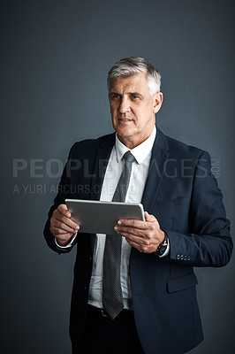 Buy stock photo Studio shot of a mature businessman using his digital tablet