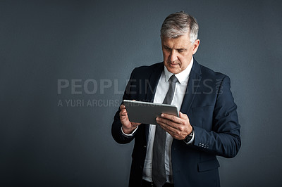 Buy stock photo Studio shot of a mature businessman using his digital tablet