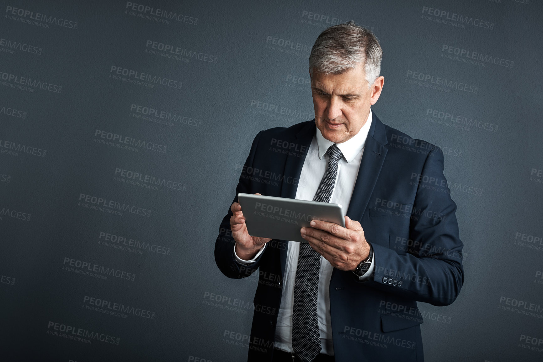 Buy stock photo Studio shot of a mature businessman using his digital tablet