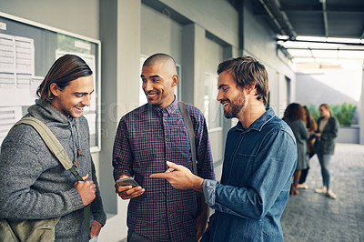 Buy stock photo Shot of a group of young students using a mobile phone together on campus