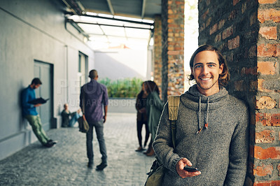 Buy stock photo Portrait of a young man using a mobile phone outdoors on campus