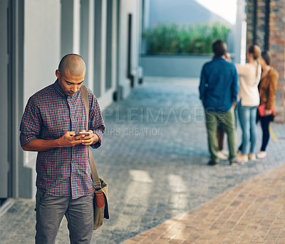 Buy stock photo Shot of a young man using a mobile phone outdoors on campus