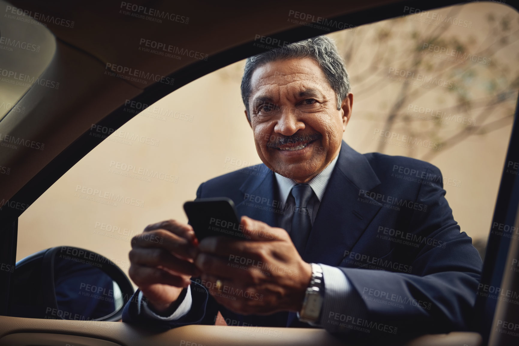 Buy stock photo Shot of a mature businessman using a phone while leaning against his car