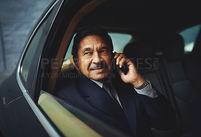 Buy stock photo Shot of a mature businessman using his phone while traveling in a car