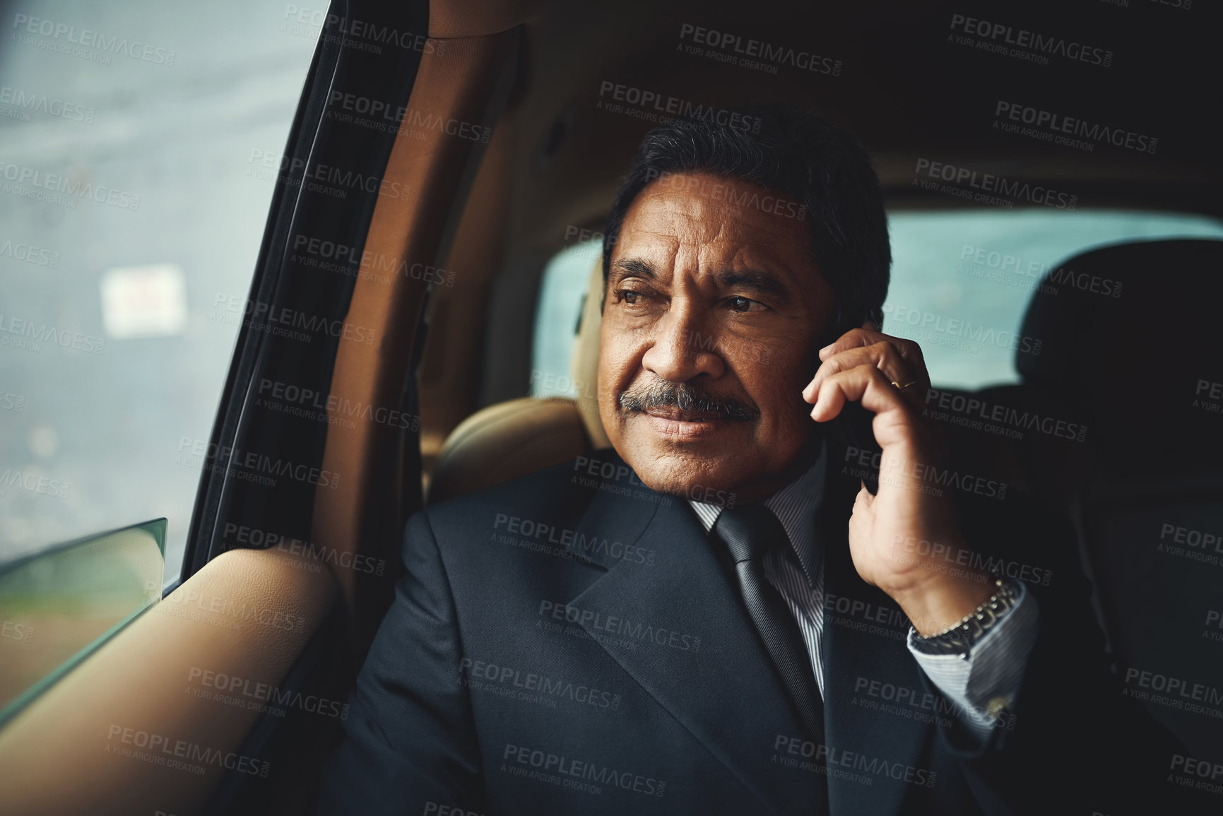 Buy stock photo Shot of a mature businessman using his phone while traveling in a car