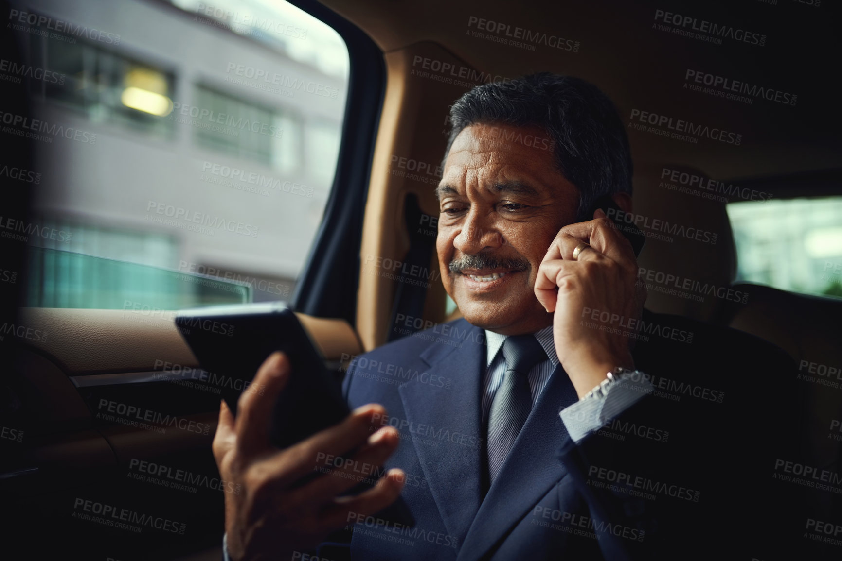 Buy stock photo Shot of a mature businessman using a phone and digital while traveling in a car