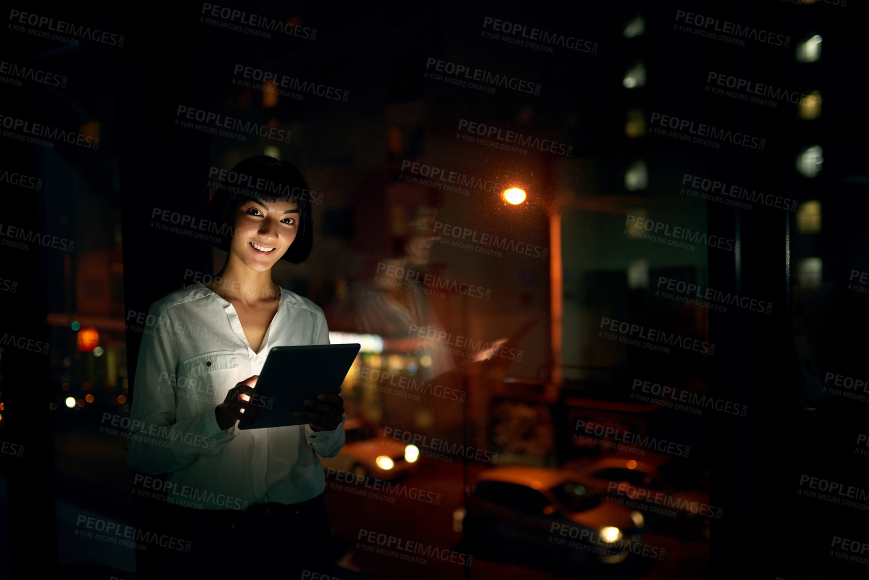 Buy stock photo Shot of an attractive young woman using a digital tablet outside in the city at night