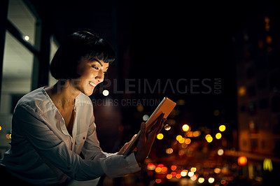 Buy stock photo Shot of an attractive young woman using a digital tablet outside in the city at night