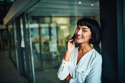Buy stock photo Shot of a young businesswoman using a mobile phone in a modern office