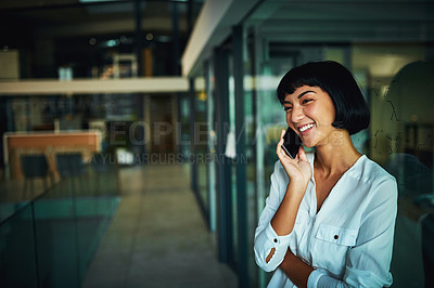 Buy stock photo Shot of a young businesswoman using a mobile phone during a late night at work