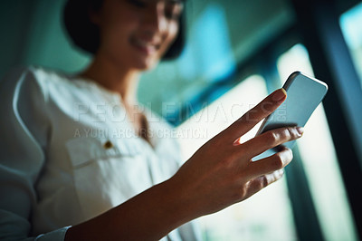 Buy stock photo Shot of a young businesswoman using a mobile phone in a modern office
