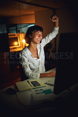 Buy stock photo Shot of a young businesswoman using a computer and cheering during a late night at work