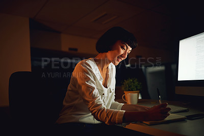 Buy stock photo Shot of a young businesswoman writing in a notebook during a late night at work
