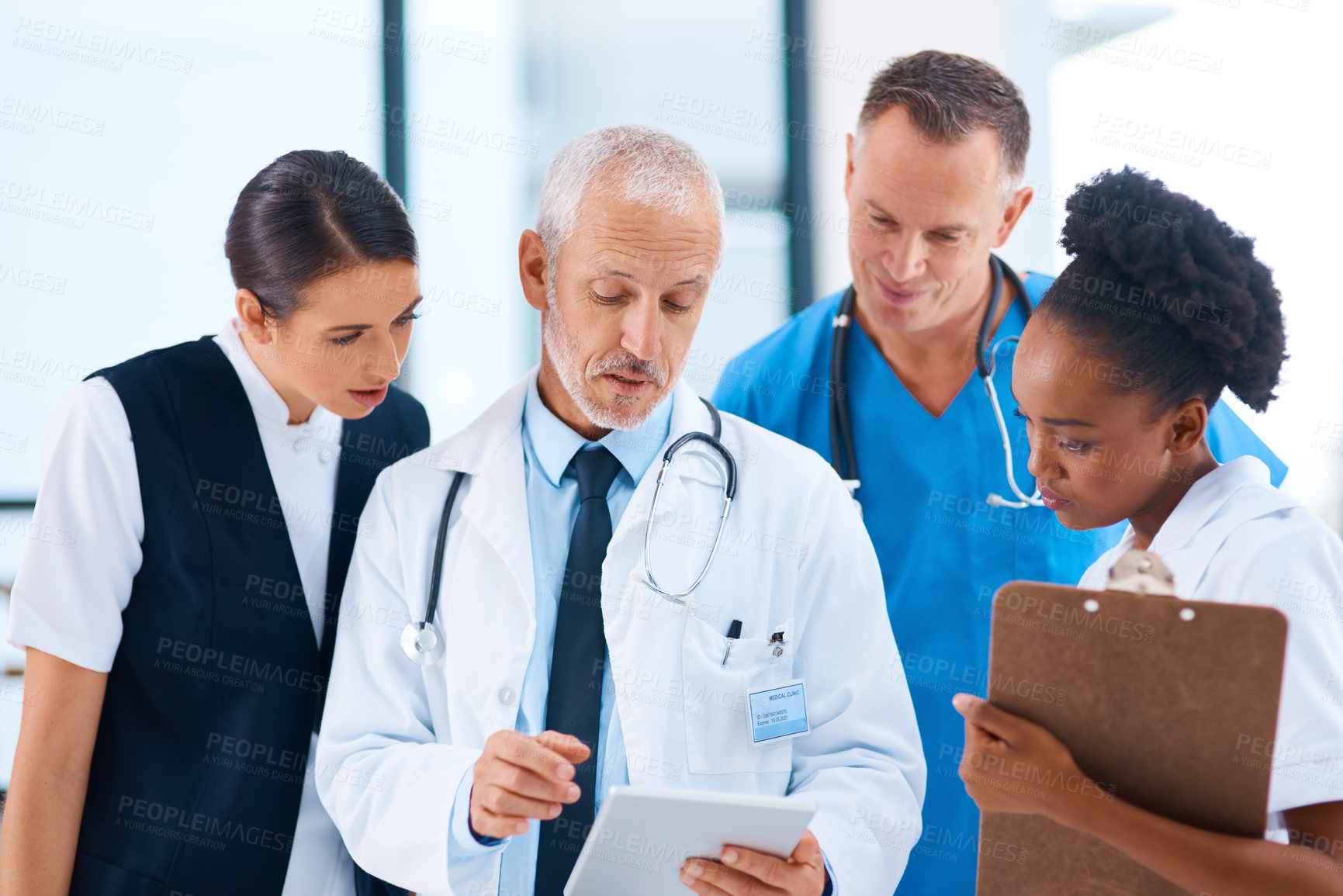 Buy stock photo Cropped shot of a group of medical professionals discussing something on a digital tablet