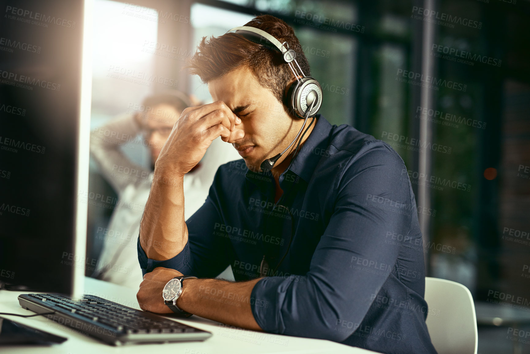 Buy stock photo Shot of a young call centre agent looking stressed out while working in an office