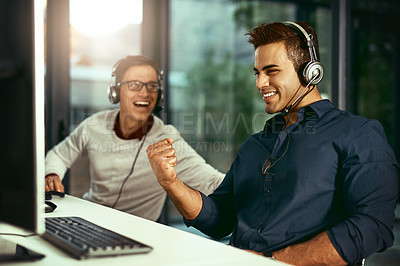 Buy stock photo Shot of two young call centre agents celebrating while working in an office