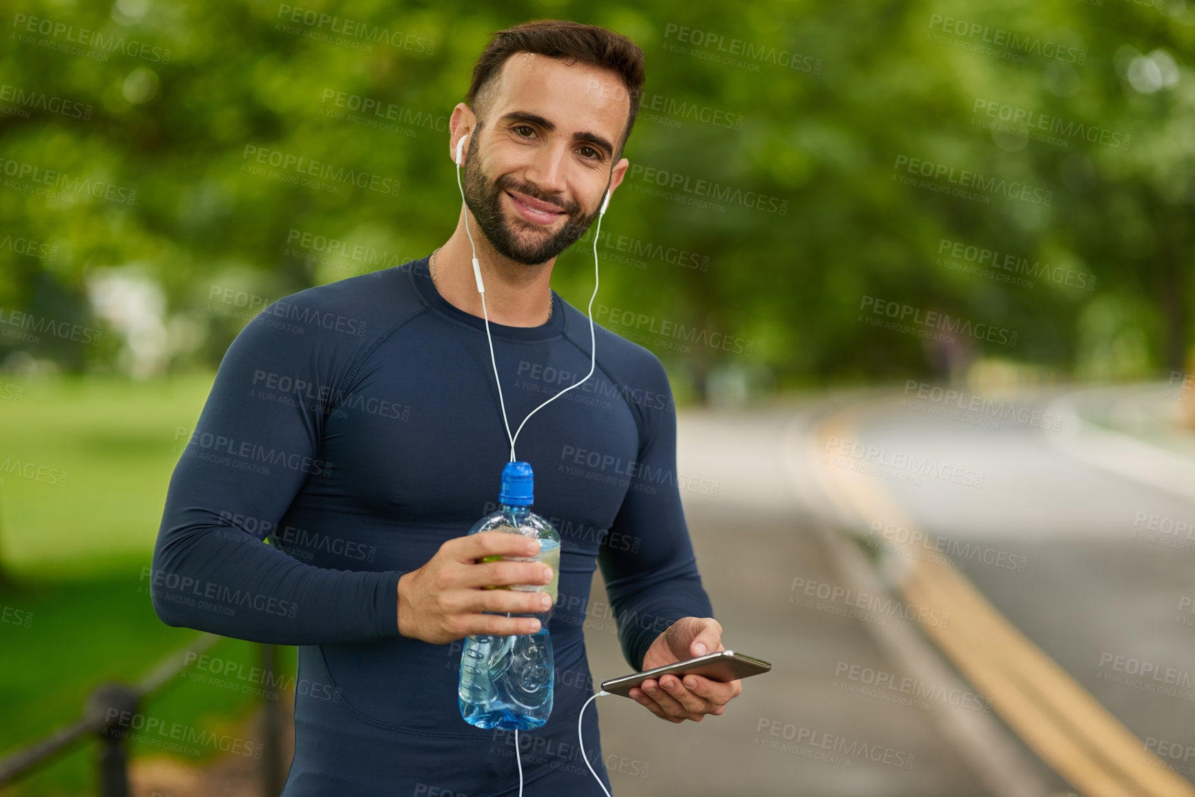 Buy stock photo Water, nature and portrait of man with earphones for listening to music, podcast or radio. Happy, hydration and male athlete with audio tech for streaming running playlist on phone at outdoor park.