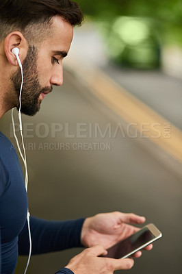 Buy stock photo Cropped shot of a handsome young male runner checking his messages during his workout