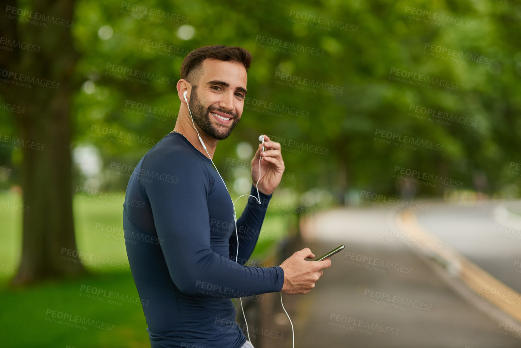 Buy stock photo Happy, nature and portrait of man with earphones for listening to music, podcast or radio. Fitness, workout and male athlete with audio tech for streaming running playlist on phone at outdoor park.