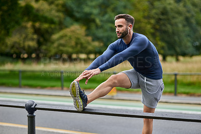 Buy stock photo Nature, fitness and man stretching legs with mobility for health, workout or running outdoor. Music, earphones and male athlete with warm up exercise on grass for cardio, sports or training in park.