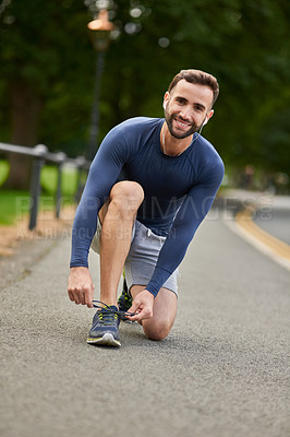 Buy stock photo Happy man, portrait and tying shoes with earphones on road for workout preparation or outdoor exercise. Young, male person or runner with smile and getting ready for fitness or training in Italy