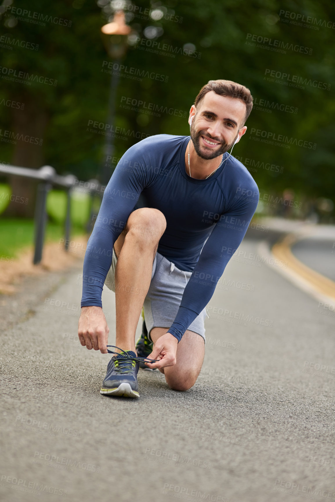 Buy stock photo Happy man, portrait and tying shoes with earphones on road for workout preparation or outdoor exercise. Young, male person or runner with smile and getting ready for fitness or training in Italy